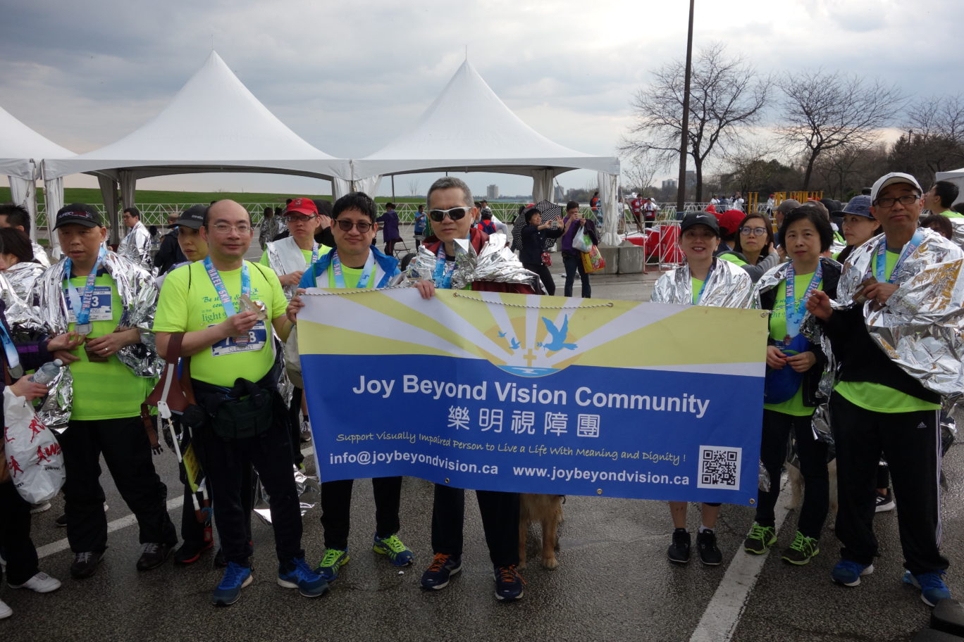 Pastor Danny and other VIP runners with their medals on the neck holding JBVC banner at the finish location