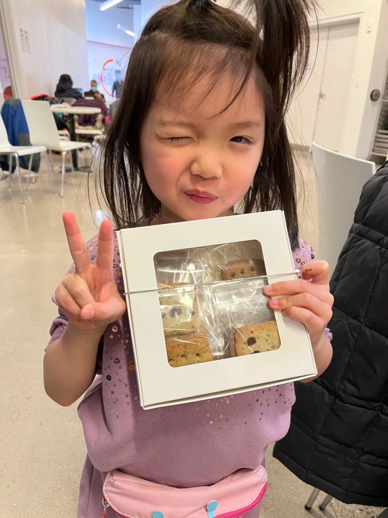 Image describing a kid holding a gift box of personal braille cookies made by herself