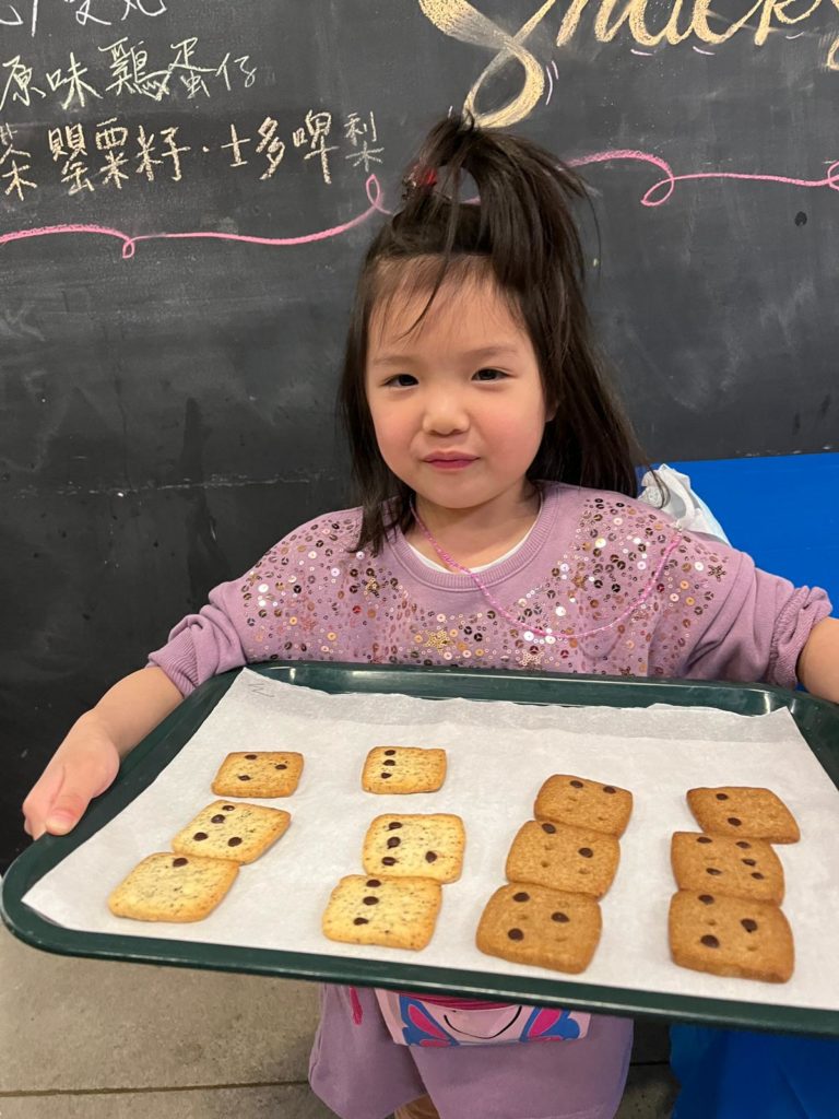 Image describing a kid holding a tray of finished product of braille cookies