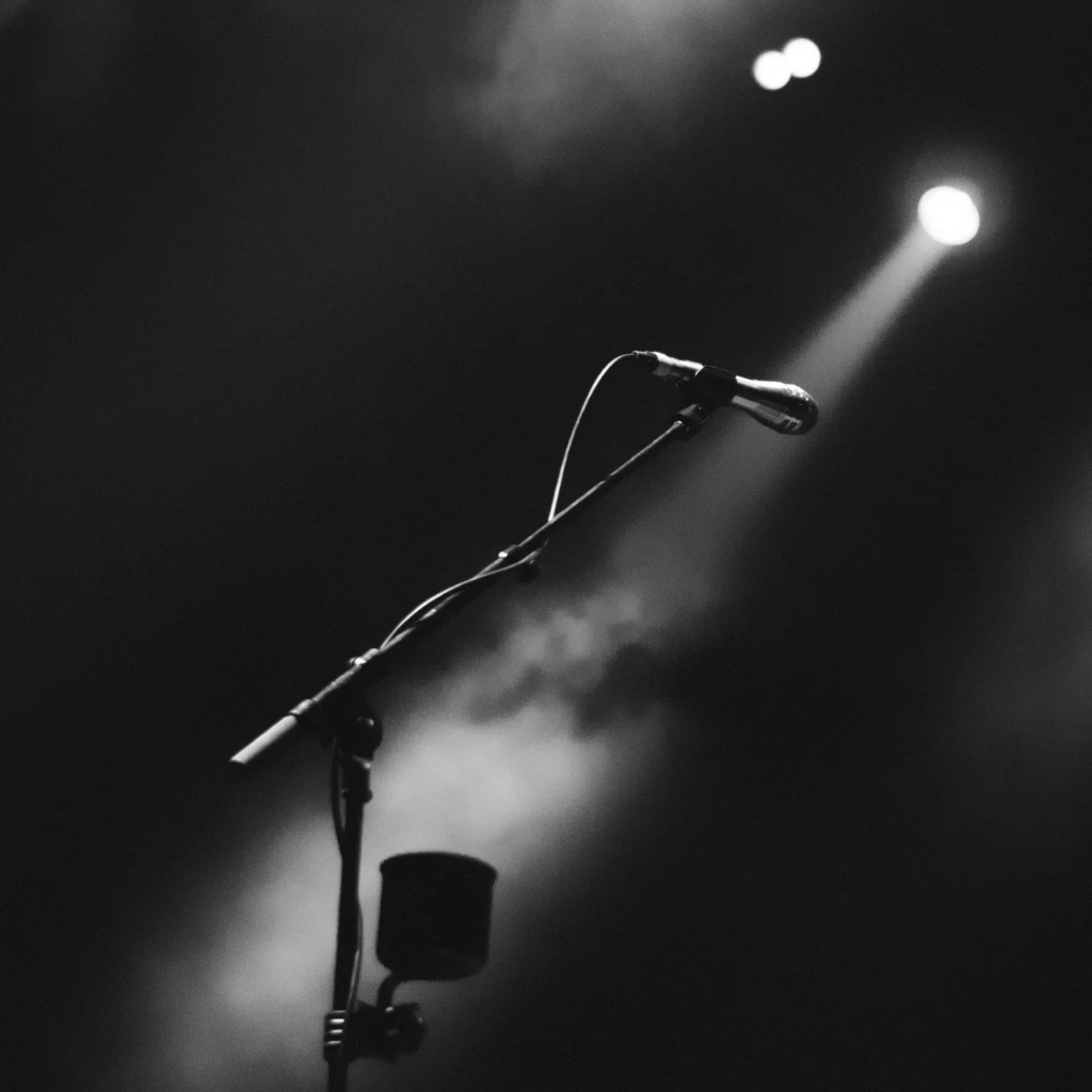 Image describing a microphone with stand in darkness projected by a beam of light