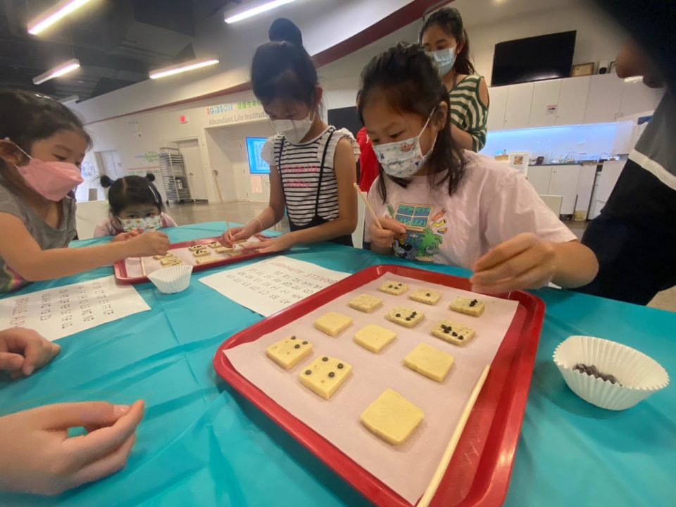 Image describing 3 kids focus on making braille cookies